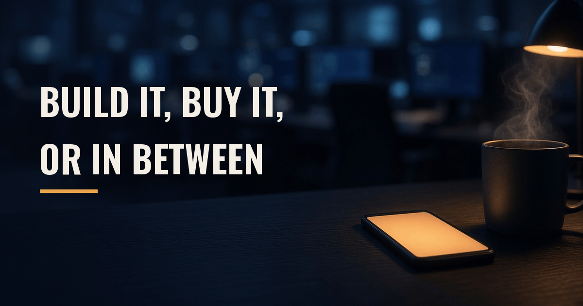 A smartphone glows amber on a dark desk beside a steaming coffee mug late at night, with an empty, softly blurred operations room behind it; the words "Build It, Buy It, or In Between" appear on the left.